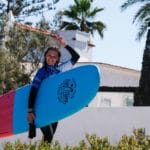 Happy surf student with surfboard after perfect surf course