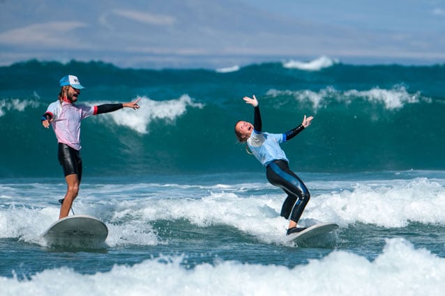 Surflehrer und Surfschüler haben riesen Spass beim Wellenreiten