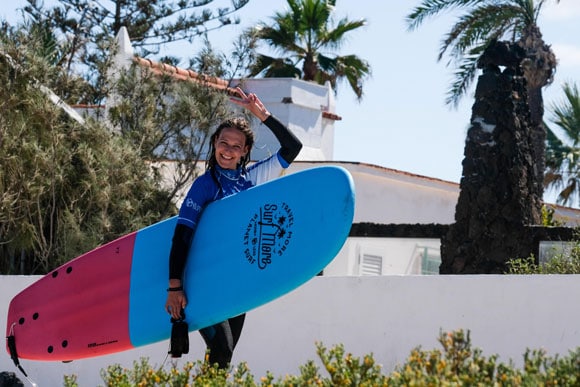 Happy Surfschüler mit Surfboard nach perfekten Surfkurs