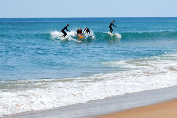 Vier Schüler beim Wellenreiten in Vieux Boucau les Bains in Frankreich